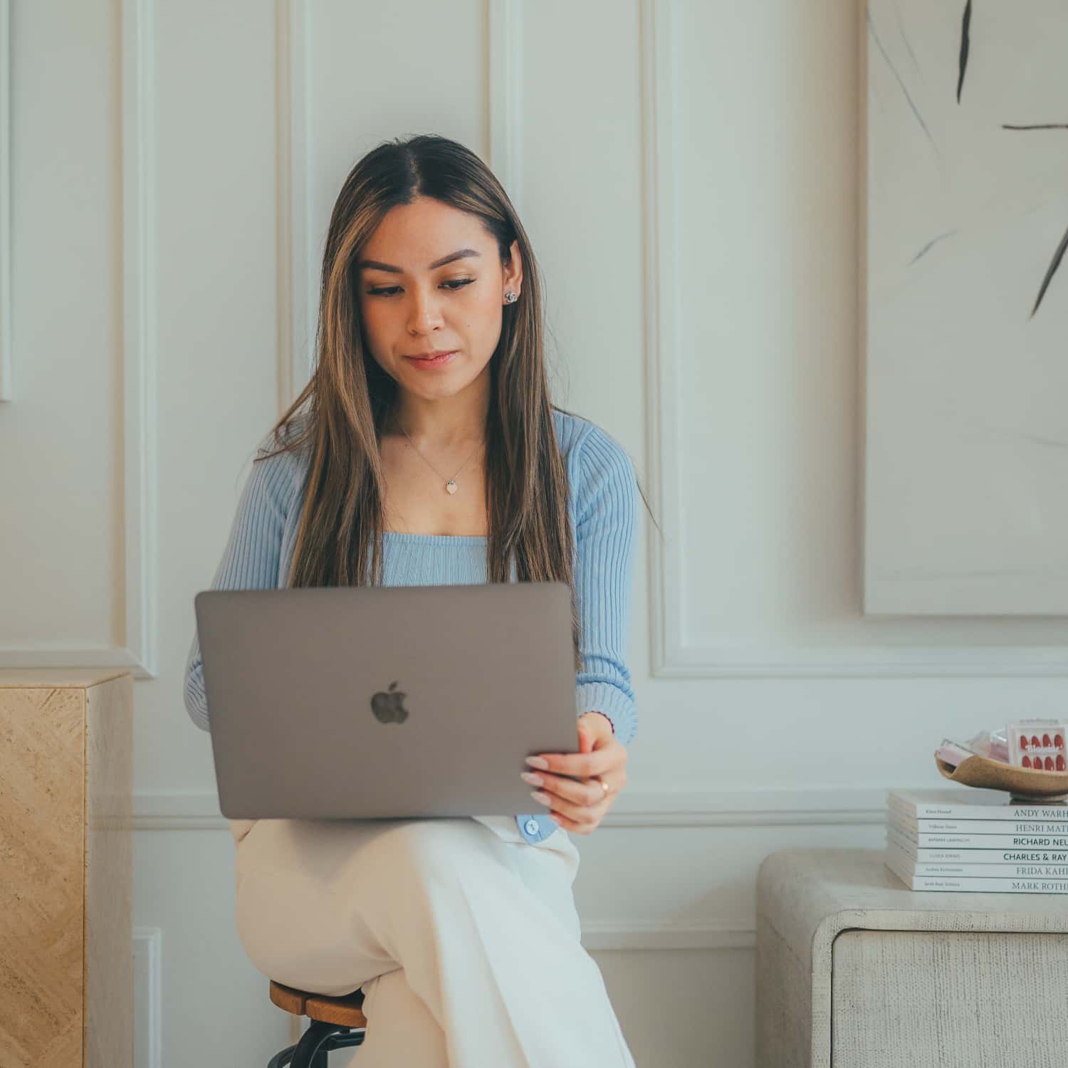 bloomie beauty founder on laptop on a stool