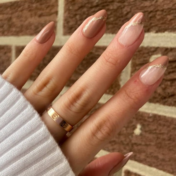 brown marble nails with gold accents worn on female hand