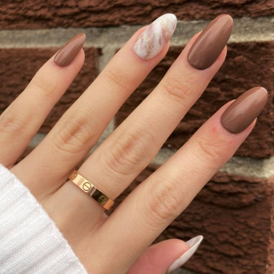Female hand wearing chocolate brown marble nails in almond shape