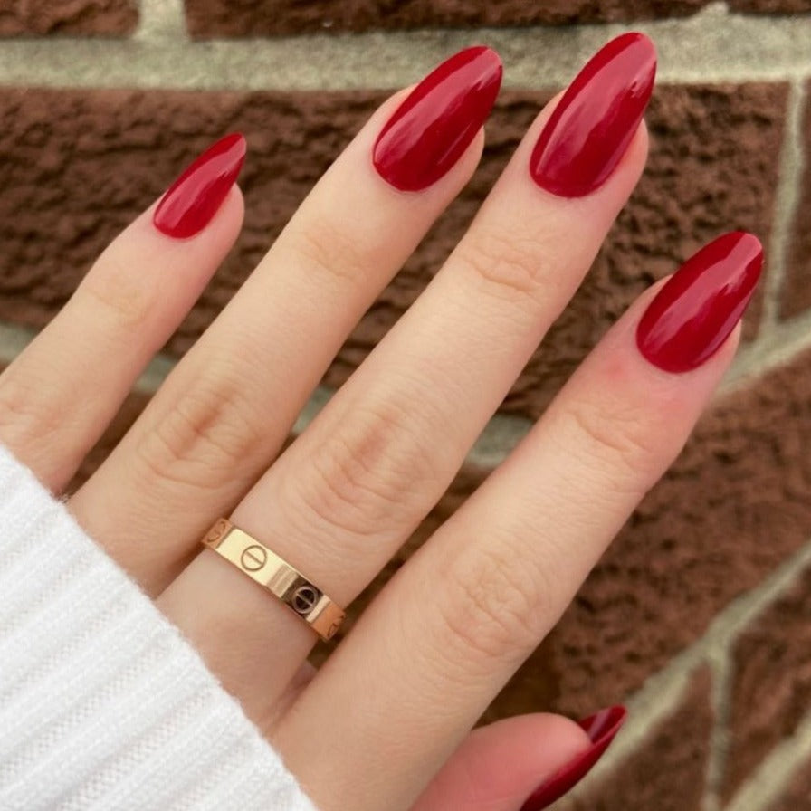 female hand dark red press on nails almond shape medium length