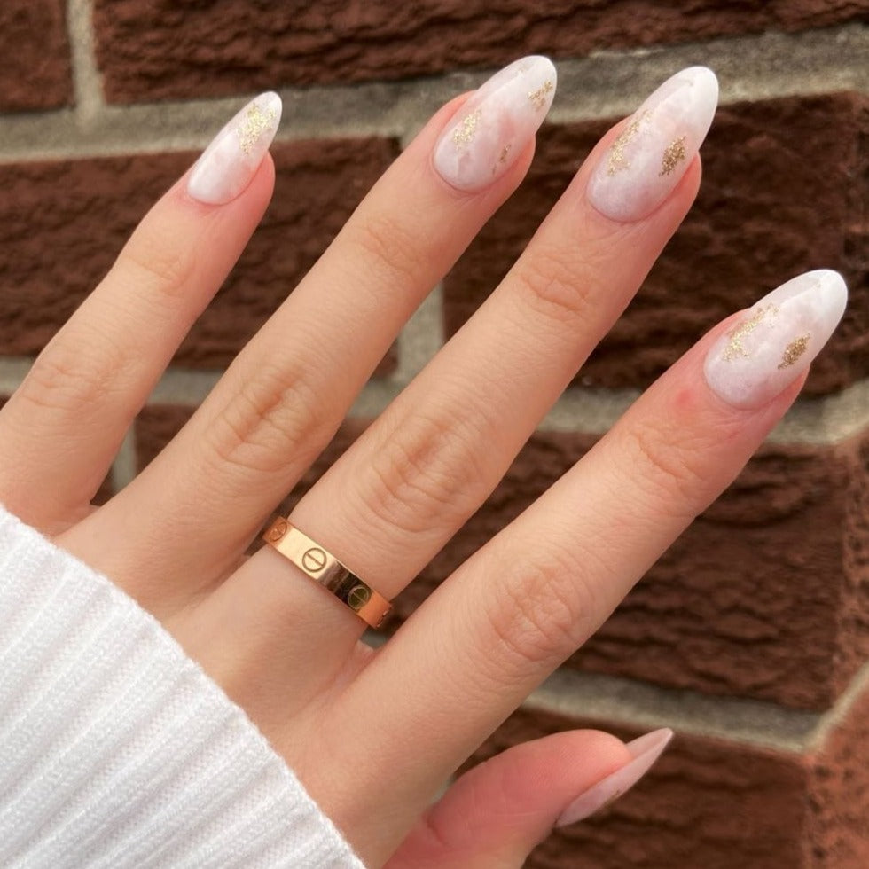 female hand wearing almond shaped light pink marble nails in medium length