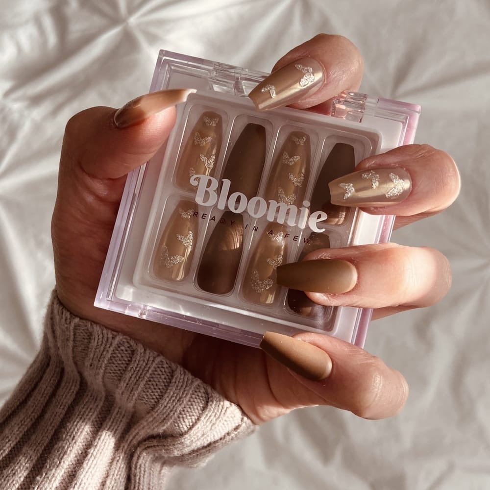 female-hand-holding-box-of-brown-butterfly-themed-press-on-nails